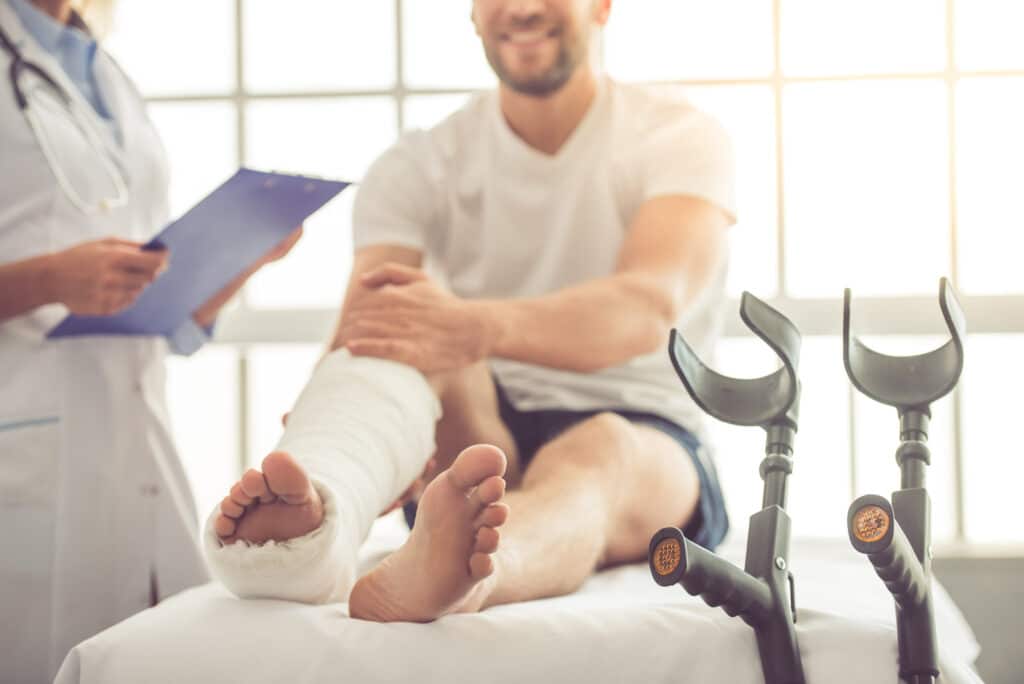 Doctor and patient Cropped image of beautiful female medical doctor listening to handsome patient with broken leg and making notes while working in her office